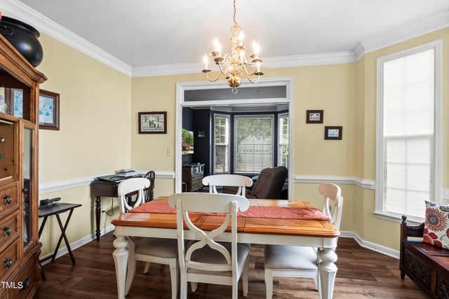 a dining room with wooden floor a chandelier a wooden table and chairs