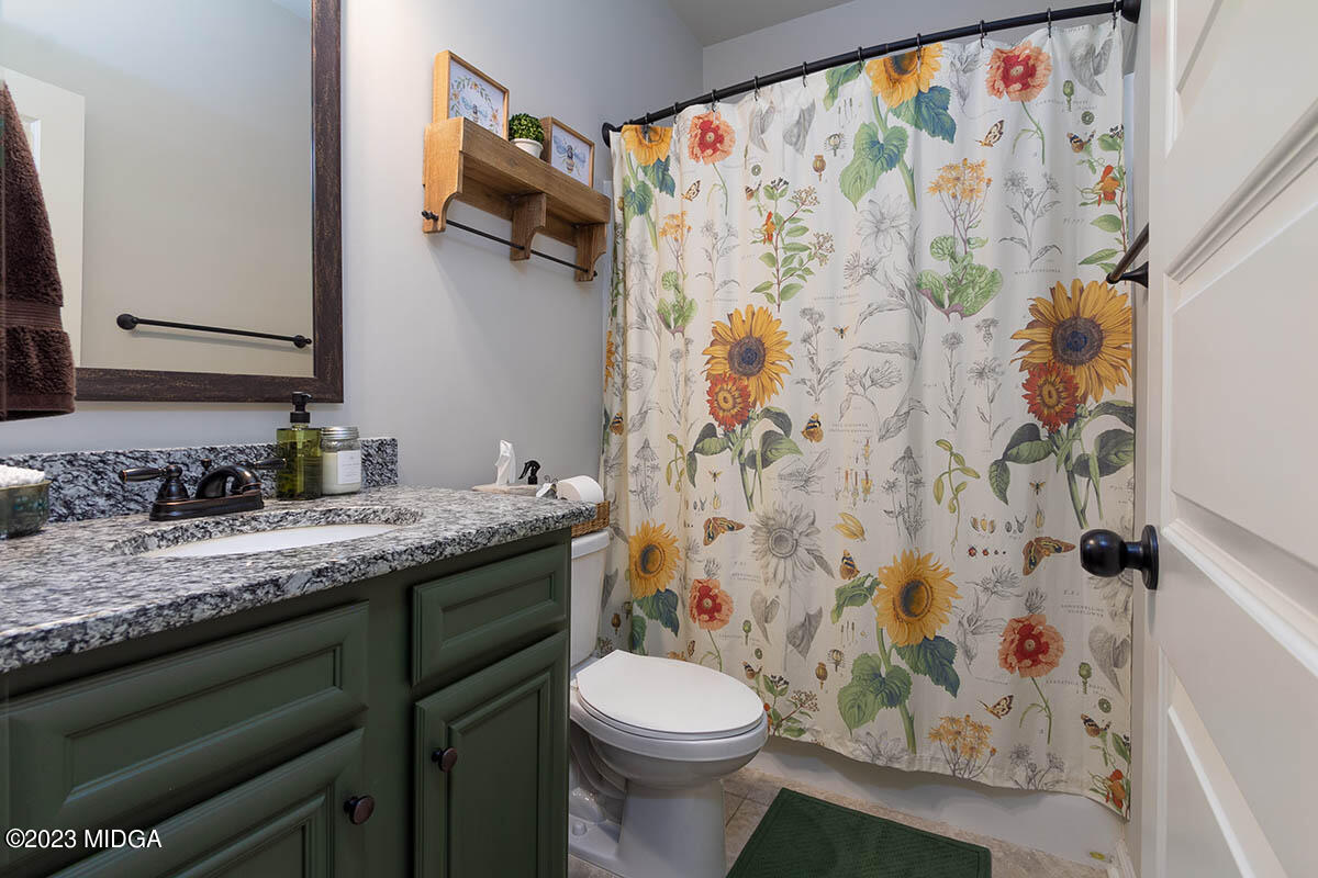 150 Homestead Circle Forsyth, GA 31029 - Photo 16 of 30 a bathroom with a granite countertop sink a toilet and a shower curtain