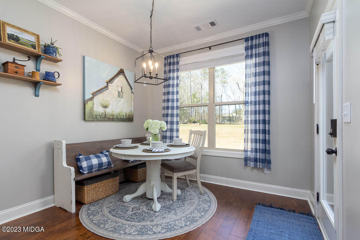 150 Homestead Circle Forsyth, GA 31029 - Photo 6 of 30 a dining room with wooden floor a chandelier a wooden table and chairs