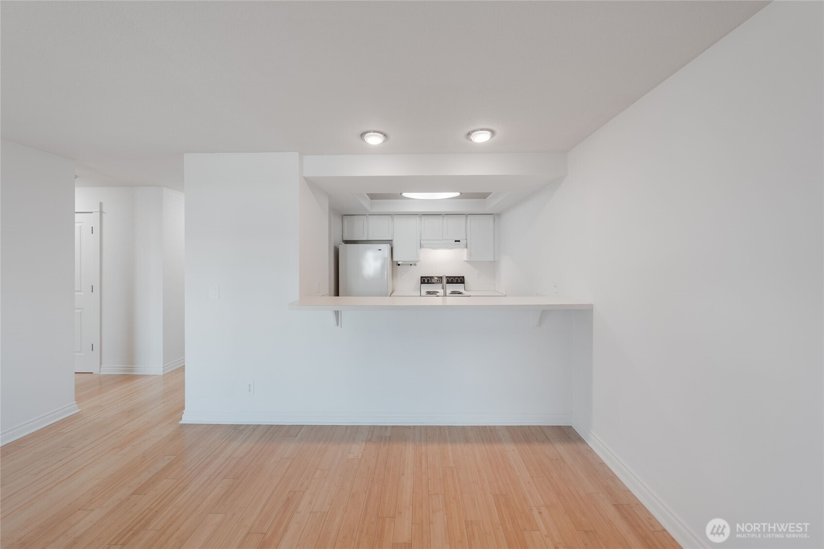 6055 35th Avenue Southwest, Unit 308 Seattle, WA 98126 - Photo 23 of 39 a view of kitchen and empty room with wooden floor