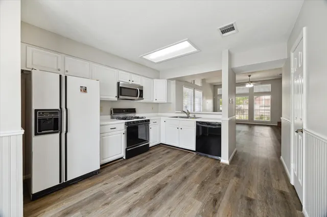 a kitchen with a refrigerator a oven a sink dishwasher and a stove with wooden floor