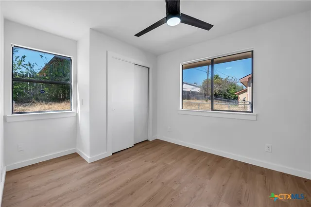 a view of an empty room with wooden floor and a window