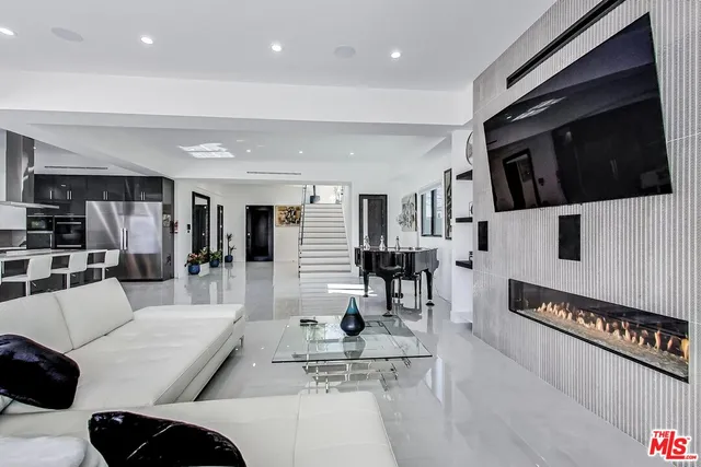 a living room with furniture a flat screen tv and kitchen view