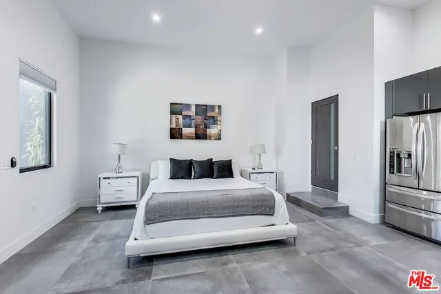 a bedroom with a bed and a refrigerator