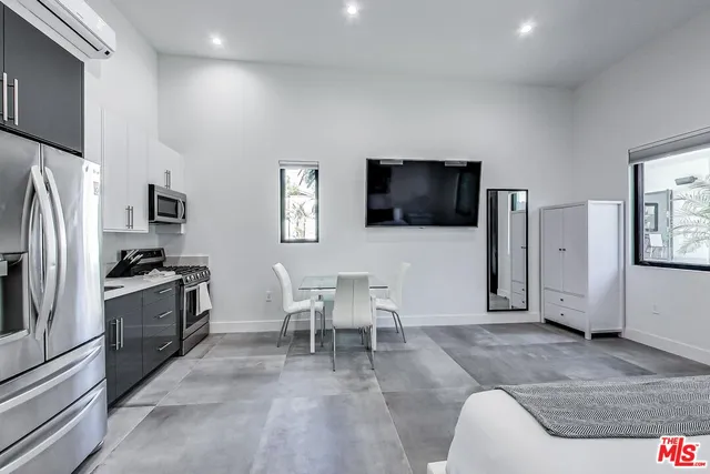 a living room with stainless steel appliances furniture and a flat screen tv