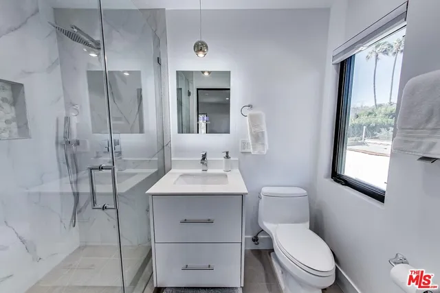 a bathroom with a toilet a sink a mirror and a shower