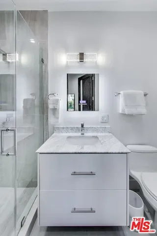 a bathroom with a granite countertop sink a mirror and shower