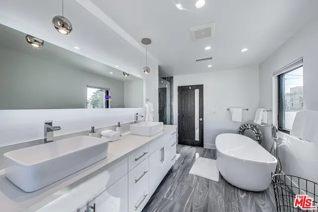 a spacious bathroom with a double vanity sink double mirror and bathtub