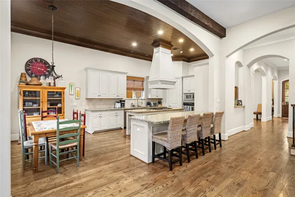 a kitchen with stainless steel appliances kitchen island granite countertop a table chairs sink and cabinets