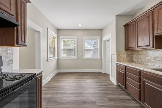 a kitchen with granite countertop wooden floors and stainless steel appliances
