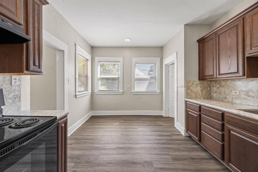 705 Madison Street Cleburne, TX 76033 - Photo 13 of 26 a kitchen with granite countertop wooden floors and stainless steel appliances