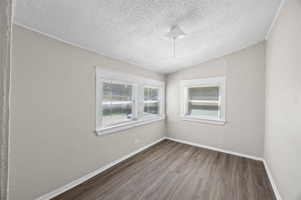 705 Madison Street Cleburne, TX 76033 - Photo 15 of 26 a view of an empty room with wooden floor and a window