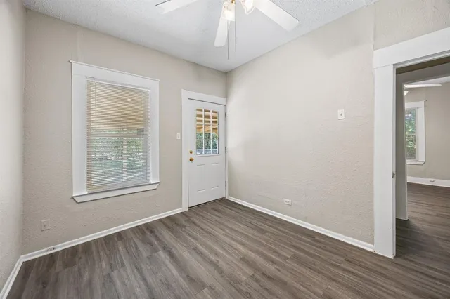 an empty room with wooden floor chandelier and windows
