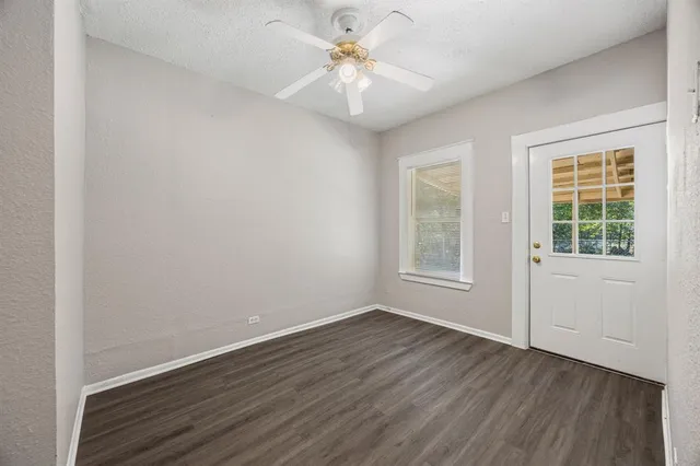 a view of a livingroom with a fan a large window with wooden floor