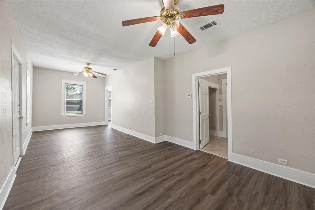 705 Madison Street Cleburne, TX 76033 - Photo 8 of 26 an empty room with wooden floor chandelier fan and windows