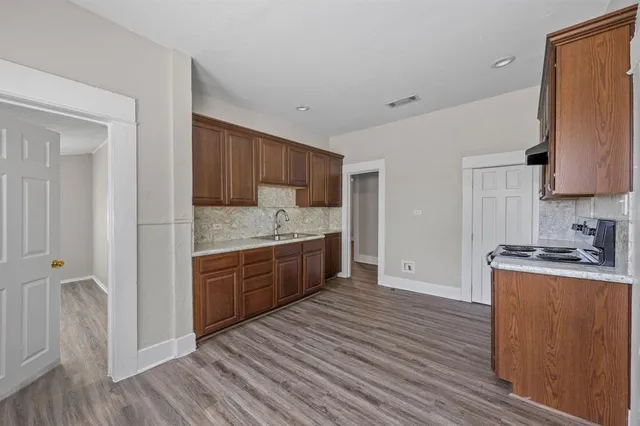 a kitchen with granite countertop a sink cabinets and wooden floor