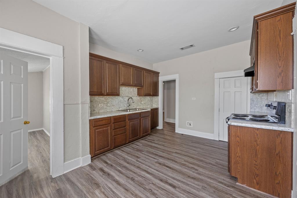 705 Madison Street Cleburne, TX 76033 - Photo 10 of 26 a kitchen with granite countertop a sink cabinets and wooden floor