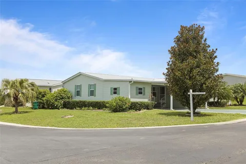 a view of a house with a big yard plants and large trees