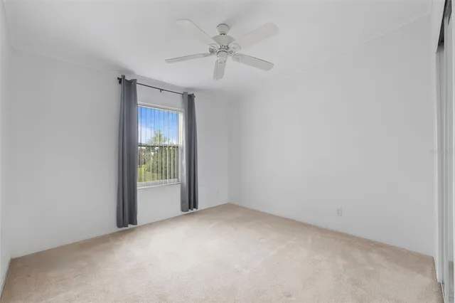 an empty room with a ceiling fan and a window
