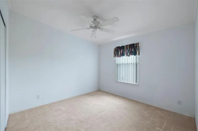 an empty room with a window and a fan