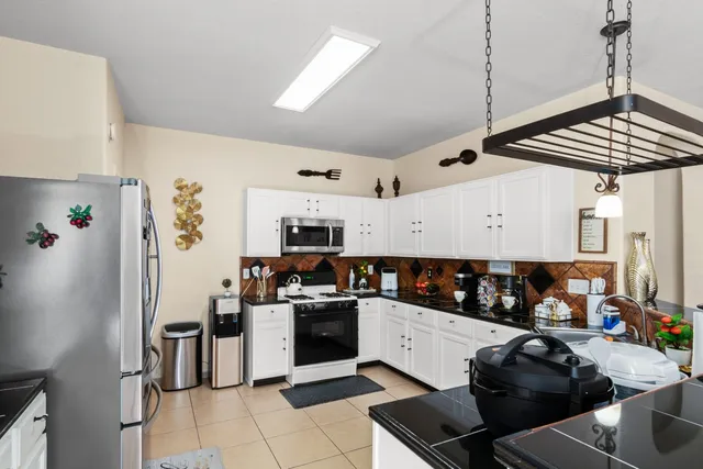 a kitchen with stainless steel appliances kitchen island granite countertop a refrigerator and a stove top oven