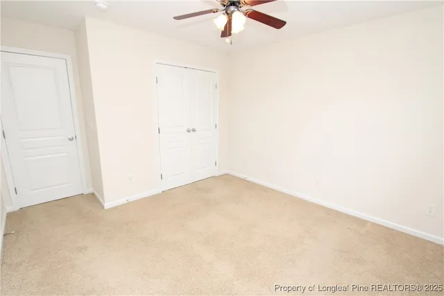 an empty room with a ceiling fan and carpet