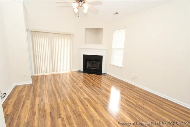 a view of empty room with wooden floor and fireplace