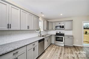6109 Bunn Simpson Road Marshville, NC 28103 - Photo 3 of 17 a kitchen with stainless steel appliances granite countertop a sink dishwasher stove and white cabinets with wooden floor