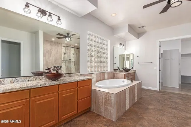 a bathroom with a granite countertop double vanity sink a mirror a bathtub and shower