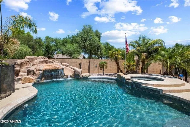 a view of swimming pool with lawn chairs and a large tree