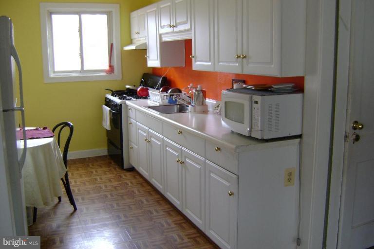 White kitchen cabinets, window, parquet floor.