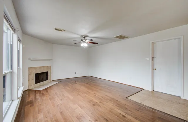 a view of empty room with wooden floor and fan