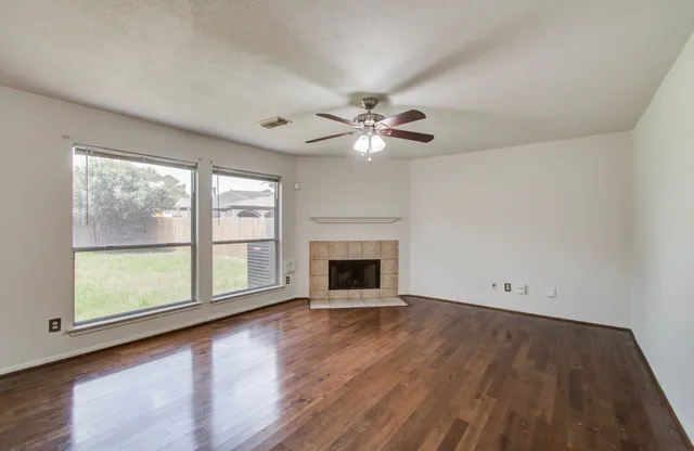 wooden floor fireplace and windows in an empty room