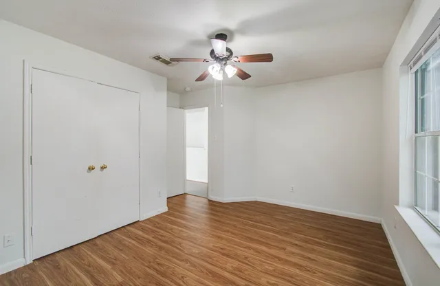 a view of empty room with wooden floor and fan