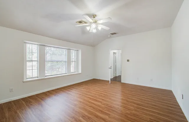 a view of an empty room with wooden floor and a window