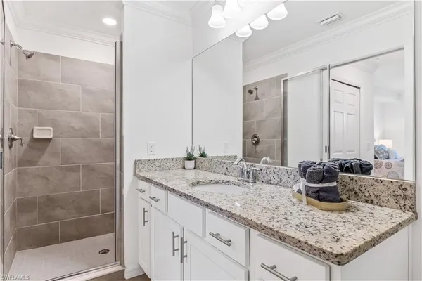 a bathroom with a granite countertop sink a mirror and shower
