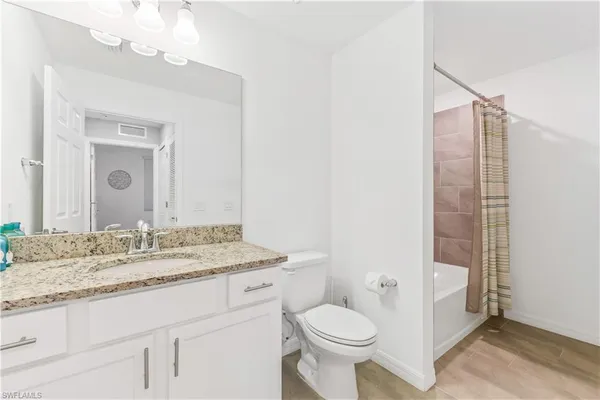 a bathroom with a granite countertop sink toilet and shower