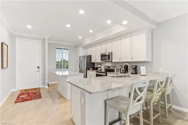 a kitchen with stainless steel appliances granite countertop a stove top oven a sink dishwasher and a refrigerator with wooden floor