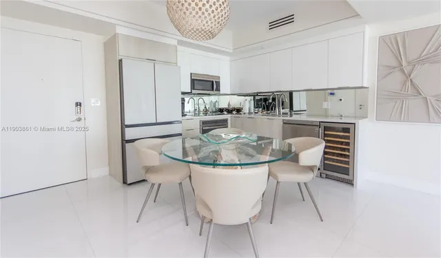 a kitchen with stainless steel appliances kitchen island granite countertop a table chairs and a refrigerator