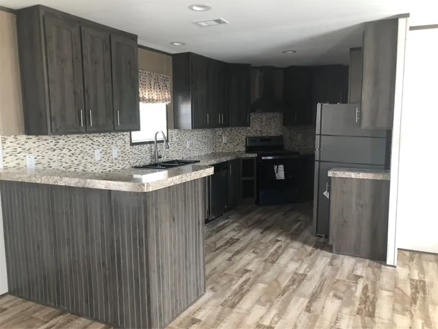a kitchen with stainless steel appliances granite countertop a sink refrigerator and cabinets