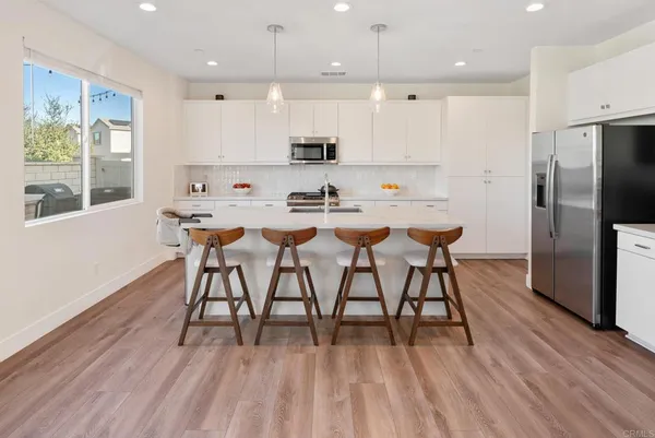 a kitchen with stainless steel appliances kitchen island granite countertop a sink a refrigerator and a couch