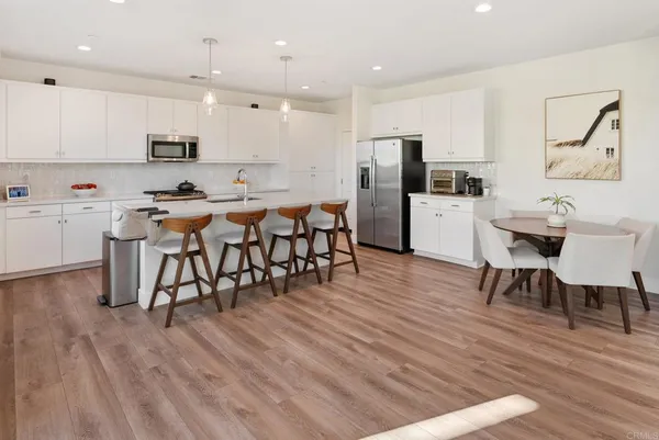 a kitchen with stainless steel appliances granite countertop a kitchen island a stove a refrigerator with a dining table and chairs