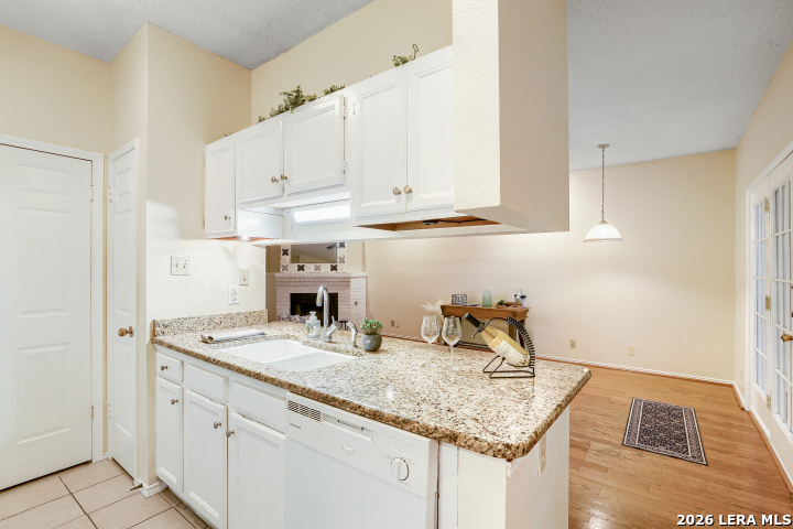 8655 Datapoint, Unit 403 San Antonio, TX 78229 - Photo 8 of 22 a kitchen with stainless steel appliances granite countertop a sink dishwasher and white cabinets with wooden floor