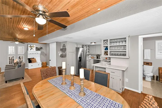 a large white kitchen with a stove a sink dishwasher and a dining table with wooden floor