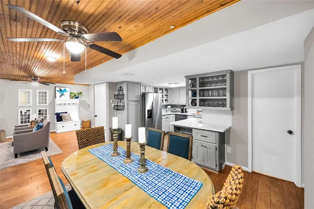 a kitchen with stainless steel appliances granite countertop a sink dishwasher and a refrigerator with wooden floor