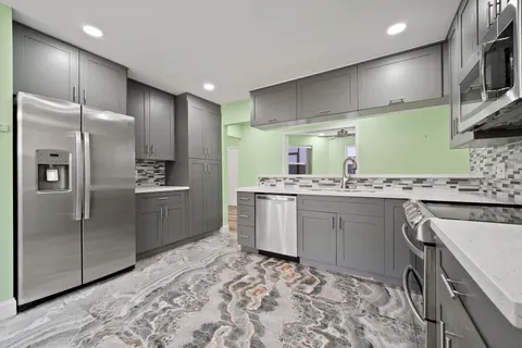 a kitchen with stainless steel appliances kitchen island granite countertop a refrigerator and a sink