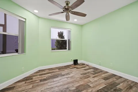 a kitchen with stainless steel appliances kitchen island granite countertop a refrigerator a stove and a sink with wooden floor