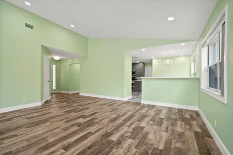 a view of an empty room with window and wooden floor