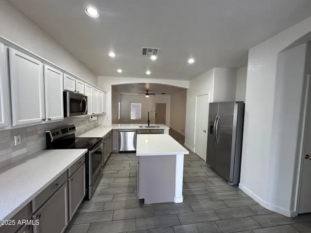 a large kitchen with stainless steel appliances kitchen island granite countertop a large counter top a refrigerator and a sink