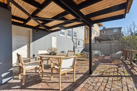 a view of a patio with table and chairs with wooden floor and fence